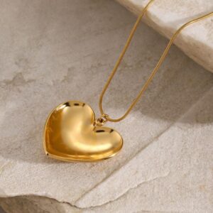 18K gold heart necklace side angle view snake chain design marble background