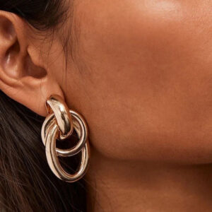 Rose gold double loop earrings worn on model side view ear close-up chunky metallic loops smooth surface