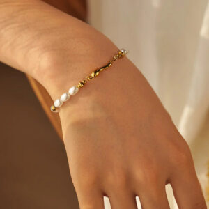 Pearl and gold bracelet on female wrist side view showing pearl alignment and gold link details with warm indoor lighting