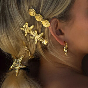 Tropical starfish and shell hair clip set worn on model, blonde hair styled with gold starfish clips and conch shell accessories, coastal jewelry styling