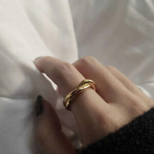 18K gold twisted ring close-up side view on female hand glossy finish intertwined bands