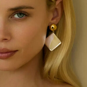 Blonde woman wearing 18K gold geometric drop earrings on left ear close-up profile shot minimalist style