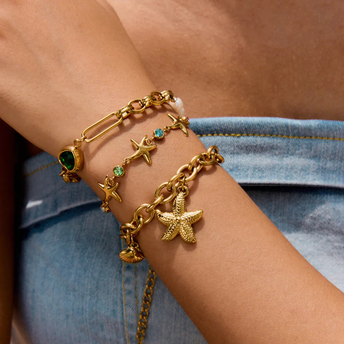 18K gold charm bracelet with pearls worn on female wrist close up