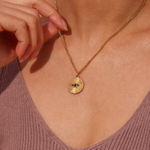 18K gold evil eye necklace worn on model, collarbone close-up, brown ribbed V-neck top, gold chain drape detail