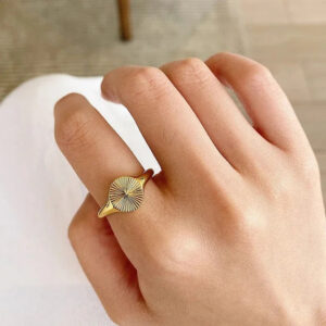 18K gold signet ring worn on hand, close-up side view showing slim gold band and textured signet face
