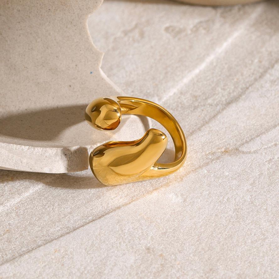 18K gold abstract open cuff ring with minimalist curved shape, glossy polished gold on textured stone