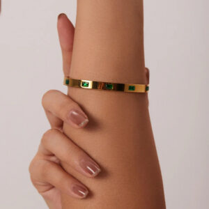 18K gold emerald bangle bracelet worn on wrist close-up lifestyle photo female model neutral manicure snug fit