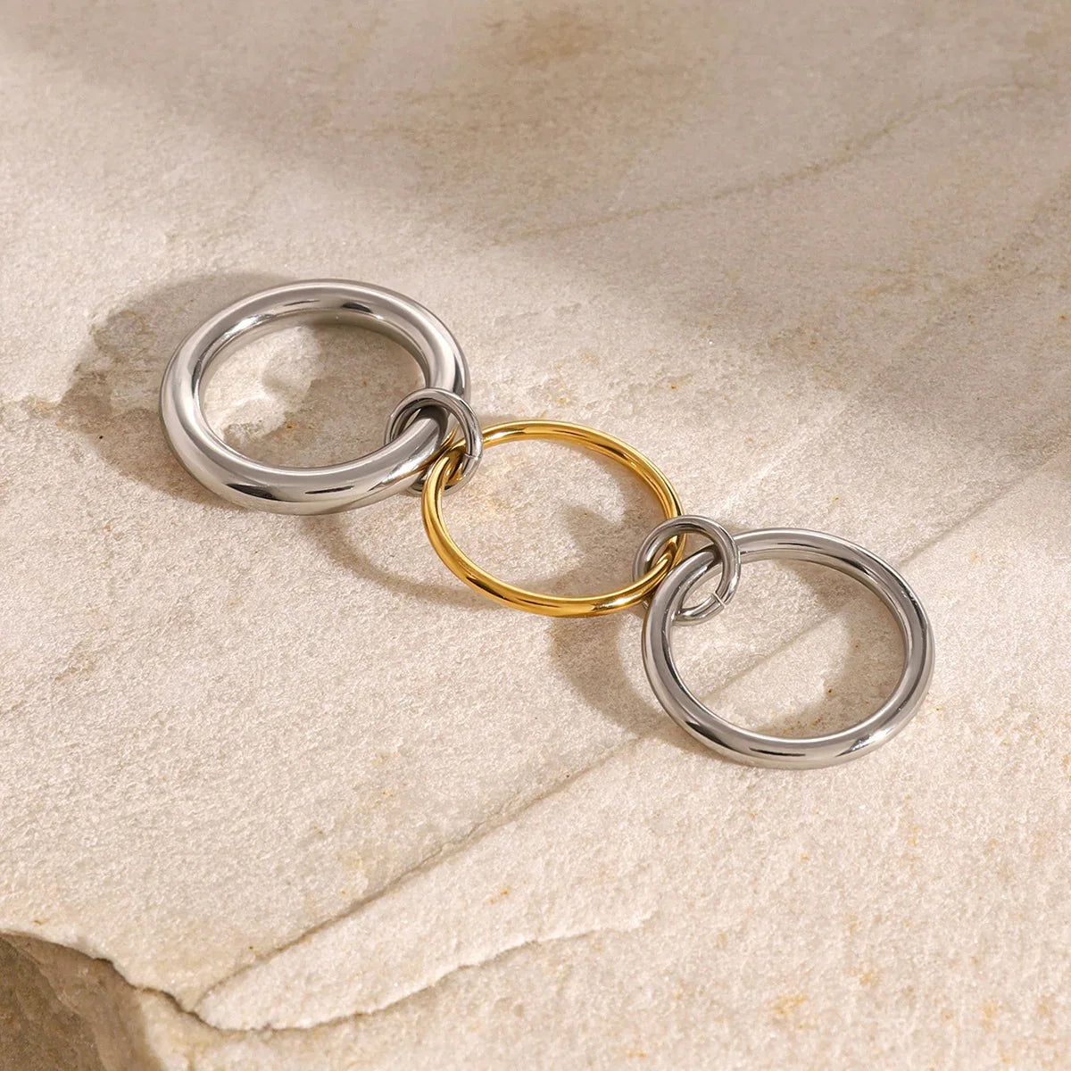 18K gold and silver two-tone stacked rings angled view - product photography on textured stone background