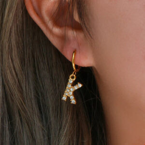 personalized gold initial letter K earrings worn on ear close-up - 18K gold drop hoop with rhinestone letter pendant on model