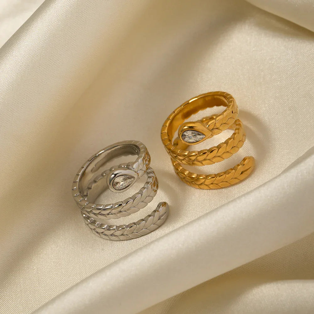 Matching 18K gold and silver serpent wrap rings flat lay on silk satin fabric dual metal finishes