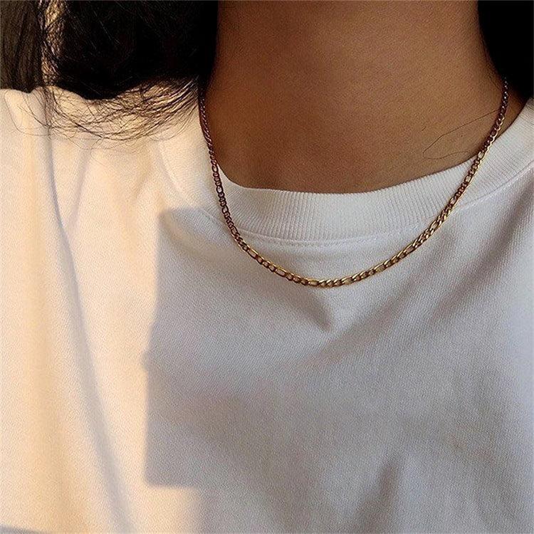 Thin flat figaro link gold necklace on model neck showing brown-golden tone minimalist plain link design