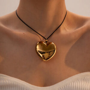 Woman wearing 18K gold heart pendant necklace at collarbone, close-up jewelry detail shot