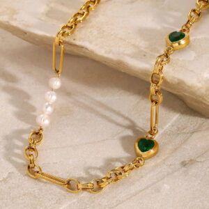 18K gold pearl necklace close-up detail, marble stone surface background, chunky gold chain with pearl strands and emerald heart pendants, hypoallergenic design