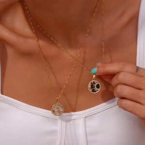 Woman wearing layered 18K gold celestial pendant necklaces dual sun moon design styled on neck