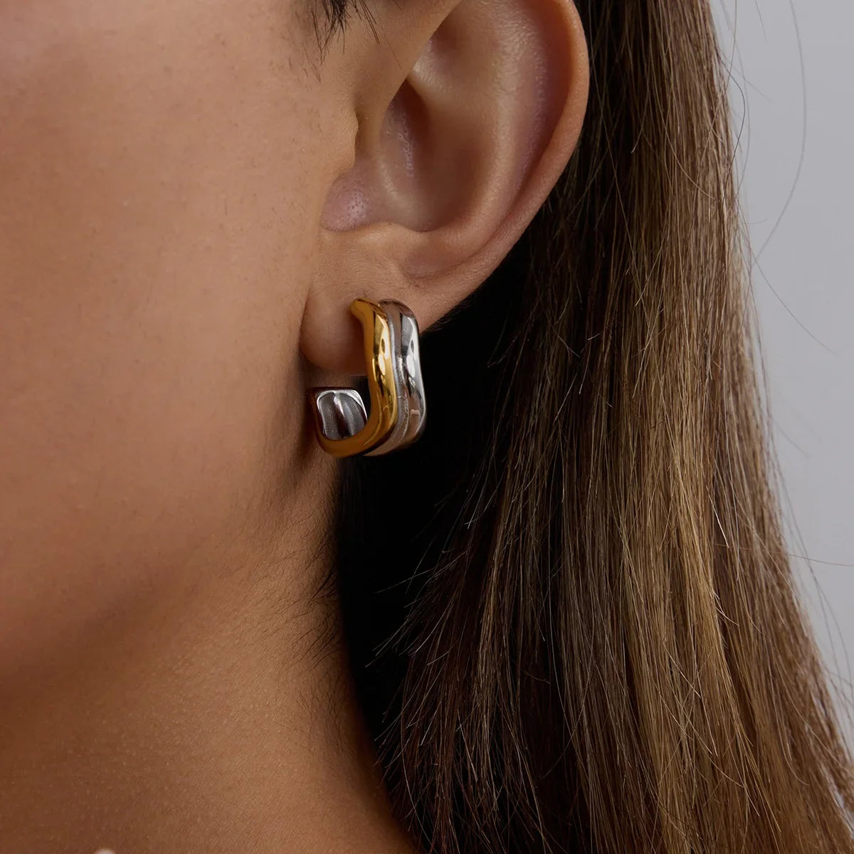 Dual-tone 18K gold silver hoop earrings on ear, side angle worn view, mixed metal finish detail