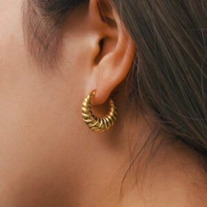 18K gold croissant hoop earrings worn on model ear showing side rear view with dark long hair