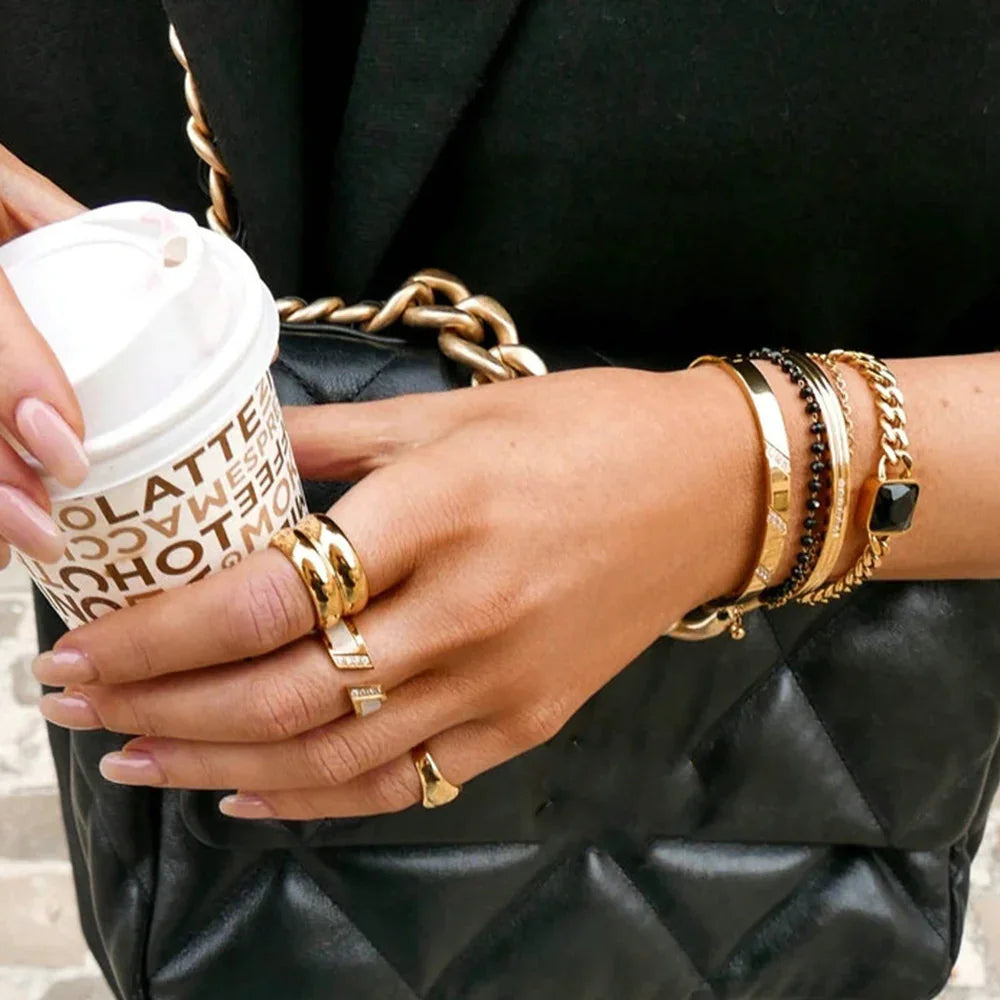 18K gold layered ring set stacked with bracelet hand holding coffee lifestyle fashion moment