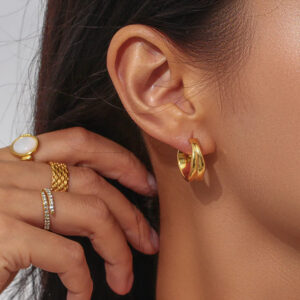 18K gold wave hoop earrings worn on ear close-up side view female model luxury jewelry