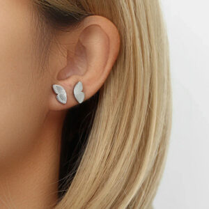 Silver tone butterfly stud earrings worn on blonde model ear close-up filigree striped detailing side profile