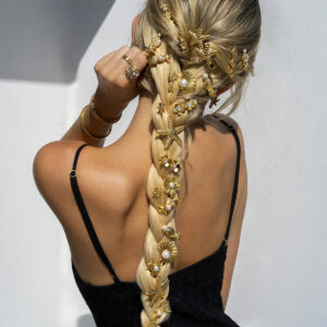 Woman wearing braided hairstyle adorned with gold starfish hair clips back three-quarter view