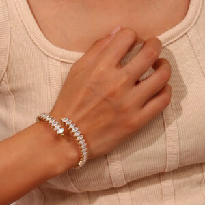 Stackable gold tennis bracelets on wrist showing round and marquise cut CZ diamonds worn on model