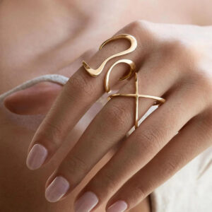 Multiple 18K gold abstract wrap rings on hand closeup detail view snake cross open ring designs gold tone