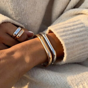 Stackable 18K gold and silver bangle bracelets worn on wrist with matching minimalist rings layered jewelry
