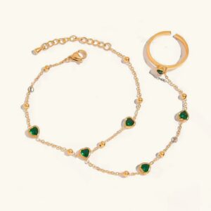 18k gold emerald heart hand chain bracelet flat lay top view with finger ring and adjustable extender chain on white background