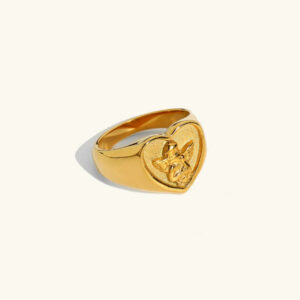 18K gold cupid heart signet ring with engraved angel motif, front flat lay view on neutral background, polished gold finish