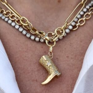 Gold cowboy boot charm necklace worn on model's neck - layered styling with mixed chain styles and star accents