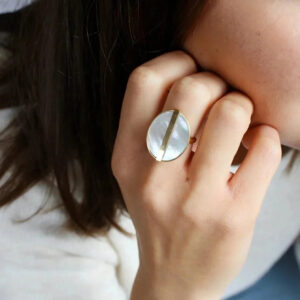 Mother-of-pearl gold ring worn on female hand close-up side view showing warm gold tone and iridescent pearl detail