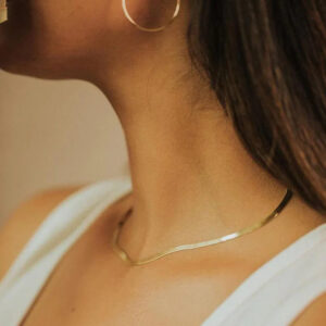 Gold herringbone choker necklace worn on model showing elegant close-up side neck view with polished flat chain design