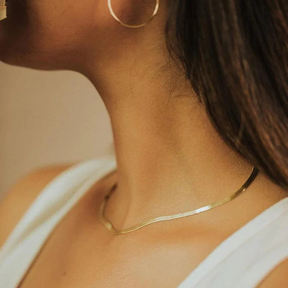 Gold herringbone choker necklace worn on model showing elegant close-up side neck view with polished flat chain design