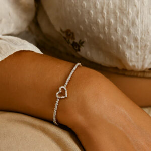18K gold heart tennis bracelet worn on wrist close-up detail showing crystal sparkle and adjustable chain fit on skin