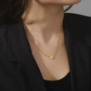Personalized gold heart initial necklace worn on female model with black blazer, delicate cable chain