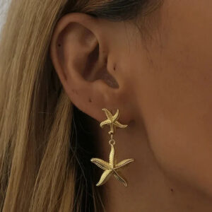 18K gold starfish drop earrings worn on ear model close-up side view gold dangle charms