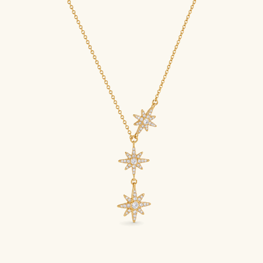 18K gold triple star cascade drop necklace flat lay product shot featuring three stacked star pendants on gold chain neutral background