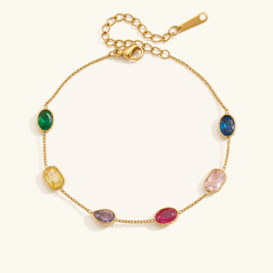 18K gold rainbow gemstone station bracelet with emerald oval sapphire ruby lavender canary crystals flat lay on white background
