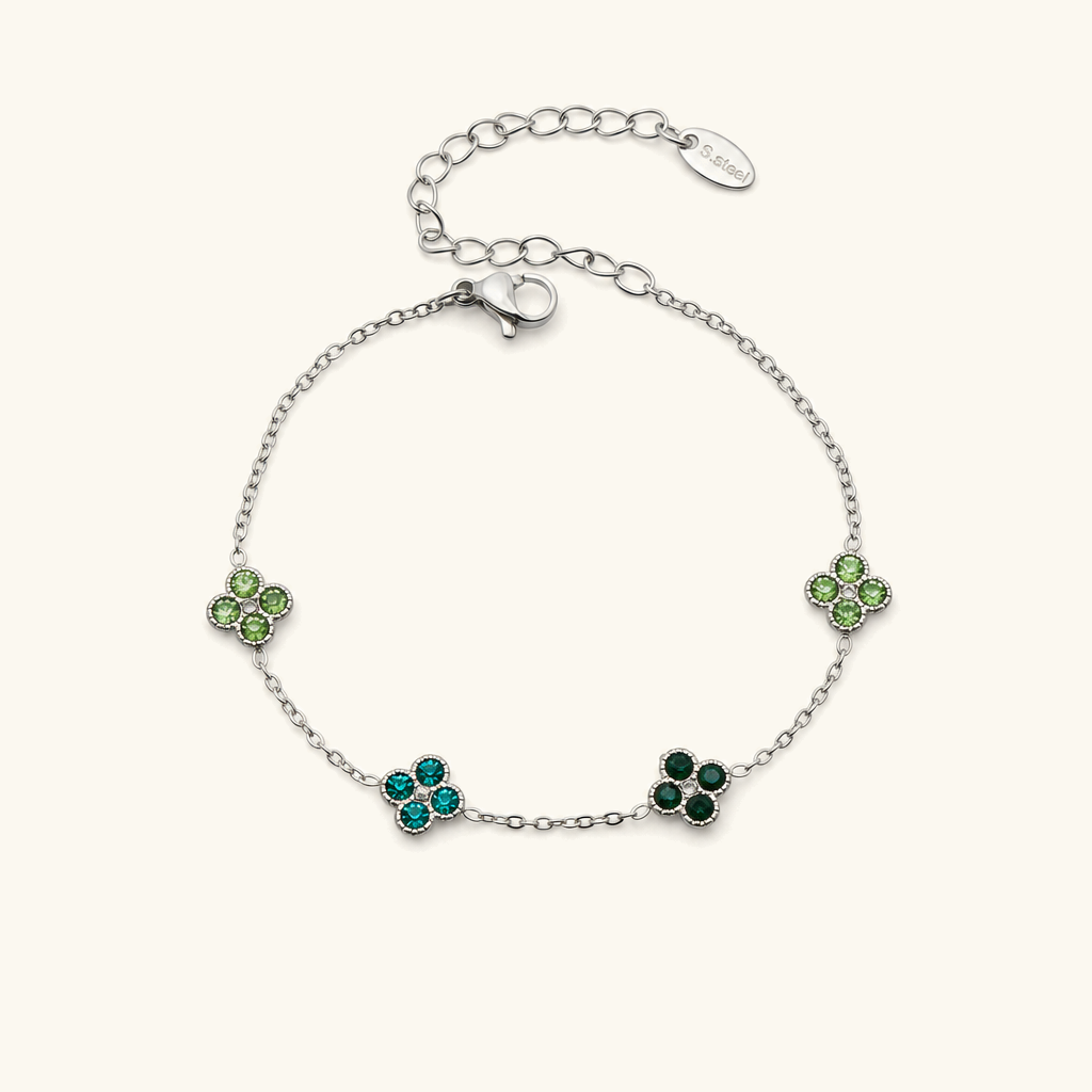Sterling silver four-leaf clover bracelet with emerald green gemstone charms, luxury accessory photography