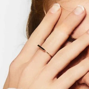 Gold bar ring worn on woman hand middle finger sleek thin band horizontal detail close-up