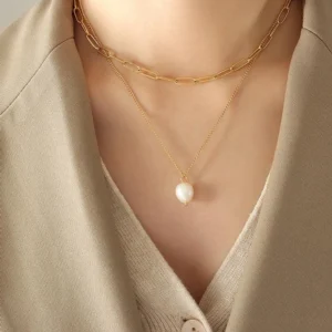 Layered gold pearl necklace worn on model showing paperclip choker chain with pearl drop close-up