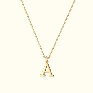 14K gold initial A pendant necklace flat lay overhead view on beige background showcasing polished box chain