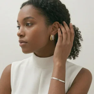Black female model wearing dual-tone hoop earrings side profile minimalist style