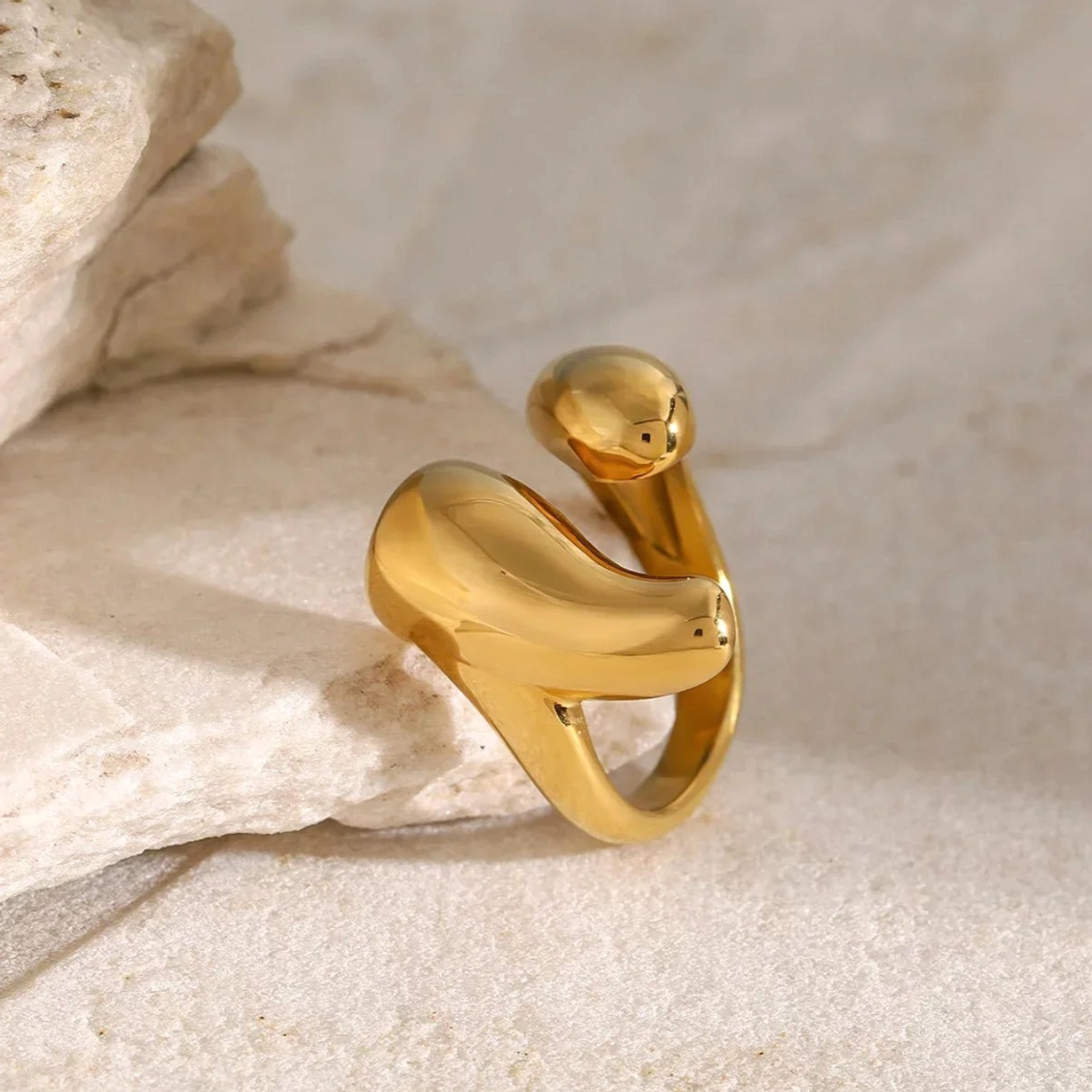 18K gold abstract open cuff ring with organic irregular shape, high-gloss polished finish on stone prop