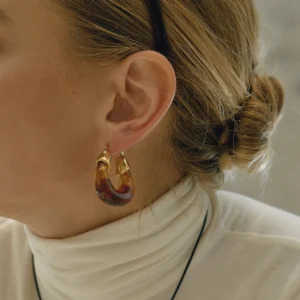 Warm brown amber enamel chunky hoop earrings worn on model's earlobe with natural fit