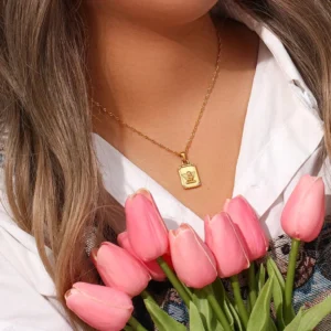 18k gold angel necklace worn on female model white blouse elegant styling with tulips