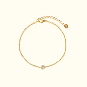 18K gold cubic zirconia anklet flat lay product shot with twisted chain design and round CZ charm on plain background
