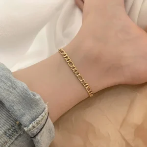 18K gold figaro chain anklet worn on female ankle with rolled denim jeans close-up side view showing comfortable fit