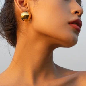 18K gold ball stud earrings close-up side view worn on model ear showing glossy metallic finish