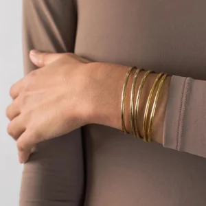 Slim gold bangle bracelets stacked on wrist - close-up side view on model